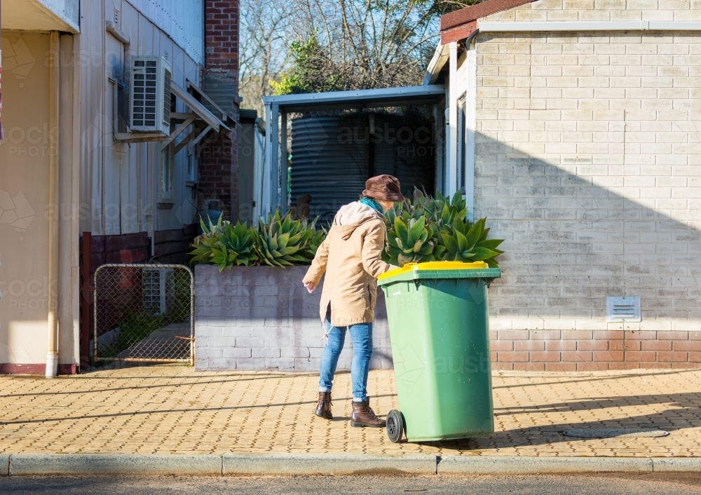 Resident taking recycling bin in off the street - Australian Stock Image