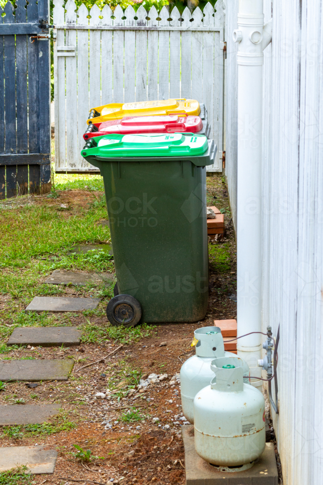 Residential wheelie bins for recycling, general, and green waste alongside house. - Australian Stock Image
