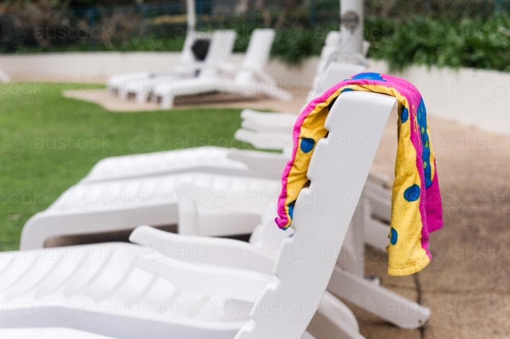 Resort sun lounges by the pool with towel draped over the back - Australian Stock Image