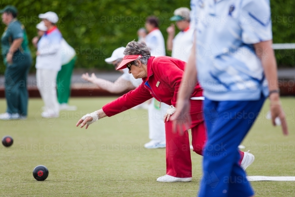 Retired woman delivering  a lawn bowl - Australian Stock Image