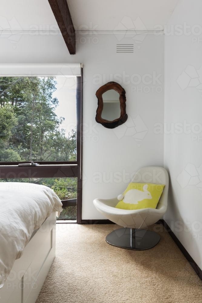 Retro beach house bedroom chair with cushion in the corner - Australian Stock Image