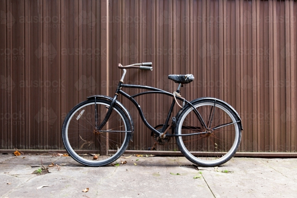 Retro bicycle against brown corrugated iron fence - Australian Stock Image