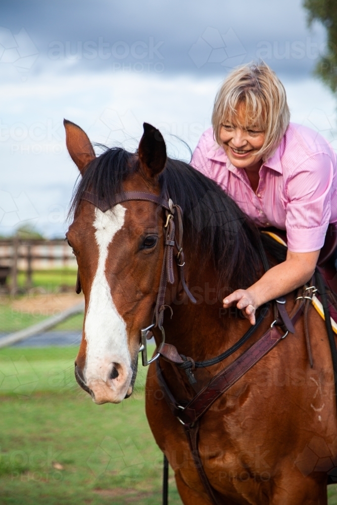 Rider hugging horse while in the saddle - Australian Stock Image