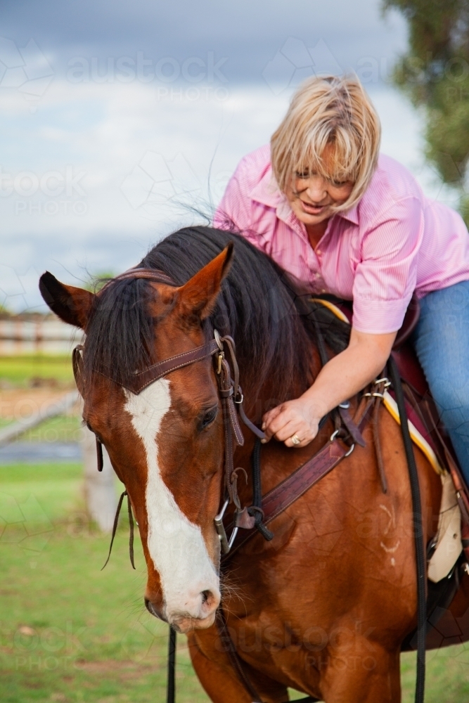 Rider hugging horse while in the saddle - Australian Stock Image