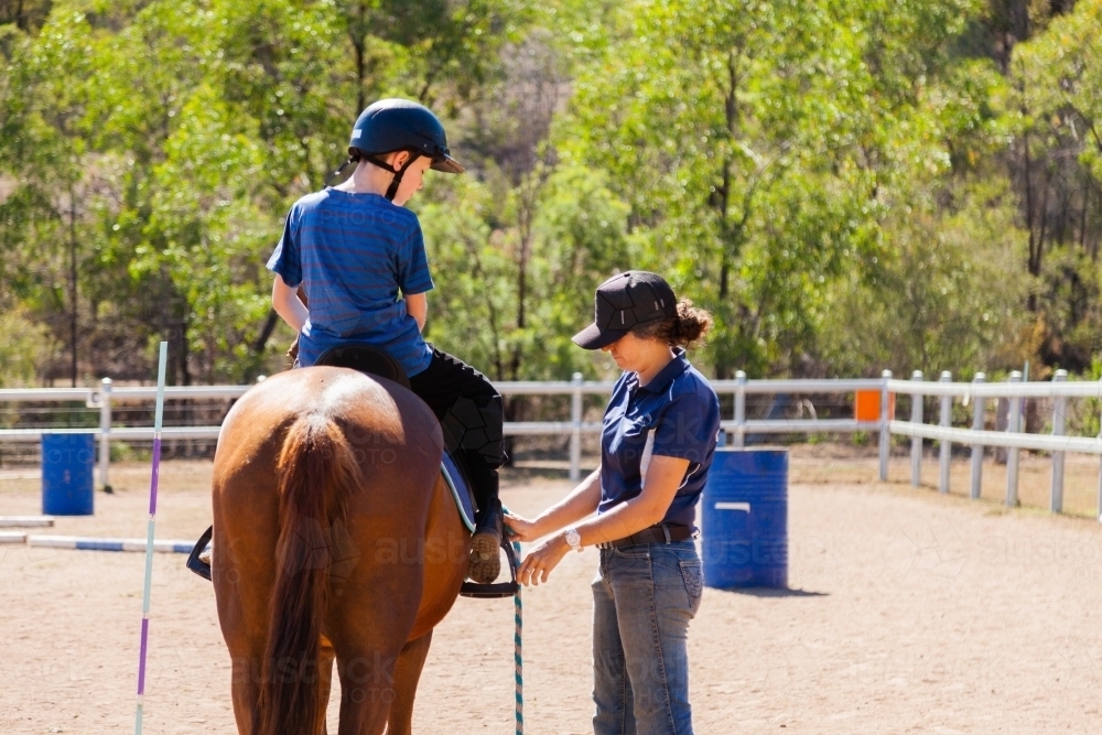 Riding instructor teaching young rider how to ride horse - Australian Stock Image