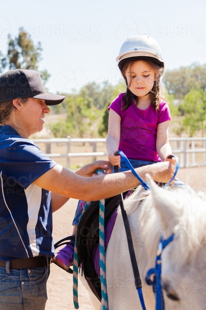 Riding instructor teaching young rider how to ride horse - Australian Stock Image