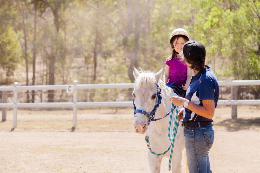 Riding instructor teaching young rider how to ride horse - Australian Stock Image