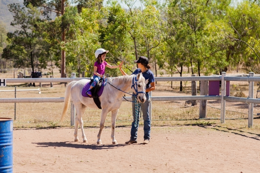 Riding instructor teaching young rider how to ride horse - Australian Stock Image