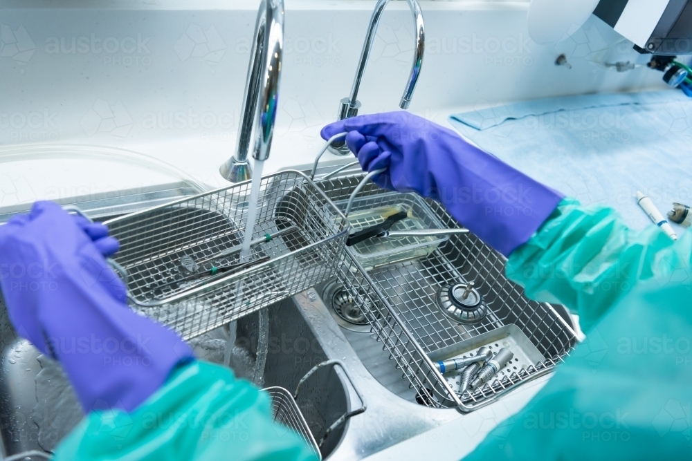 Image of Rinsing and cleaning dental instruments under running water ...