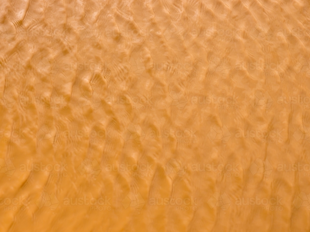 Ripple pattern on orange/brown muddy water - Australian Stock Image