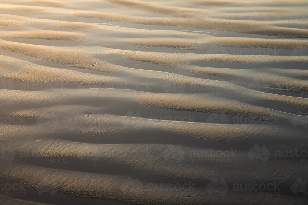 Ripple patterns of sand and water on a beach - Australian Stock Image