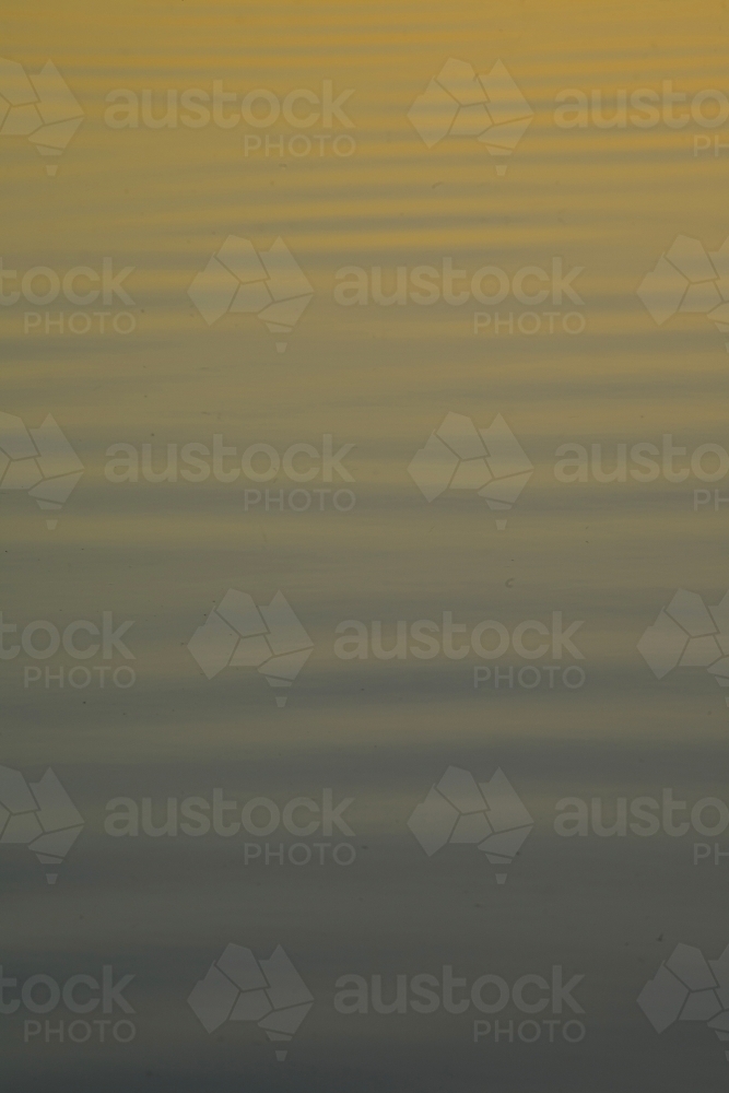 Ripples on a serene lake reflecting sunset colours - Australian Stock Image