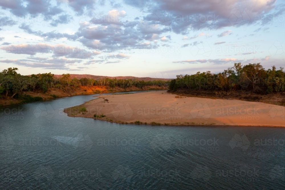 River winding around a sandy bank in rural area at sunset - Australian Stock Image