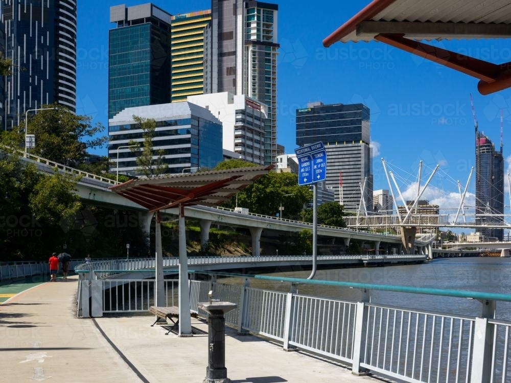 Riverside shared pathway with drinking fountain, shelter and pedestrian in the background. - Australian Stock Image