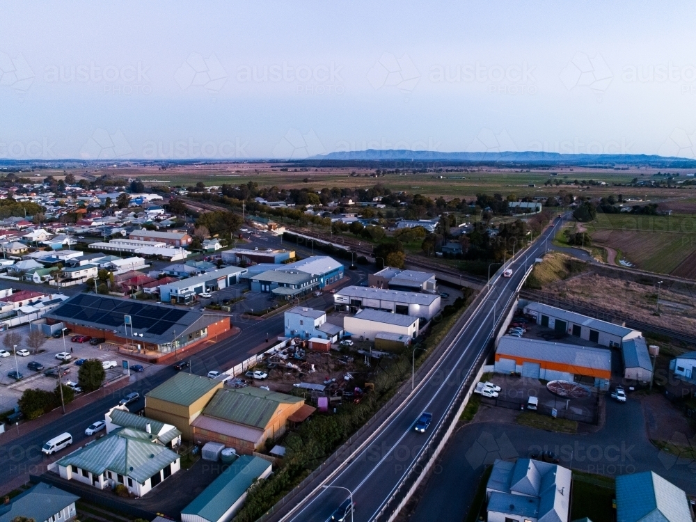 Road heading out of country town over railway line at dusk - Australian Stock Image