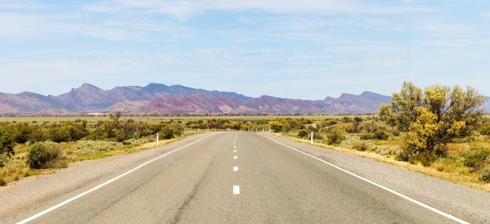 Road heading towards rugged mountains - Australian Stock Image