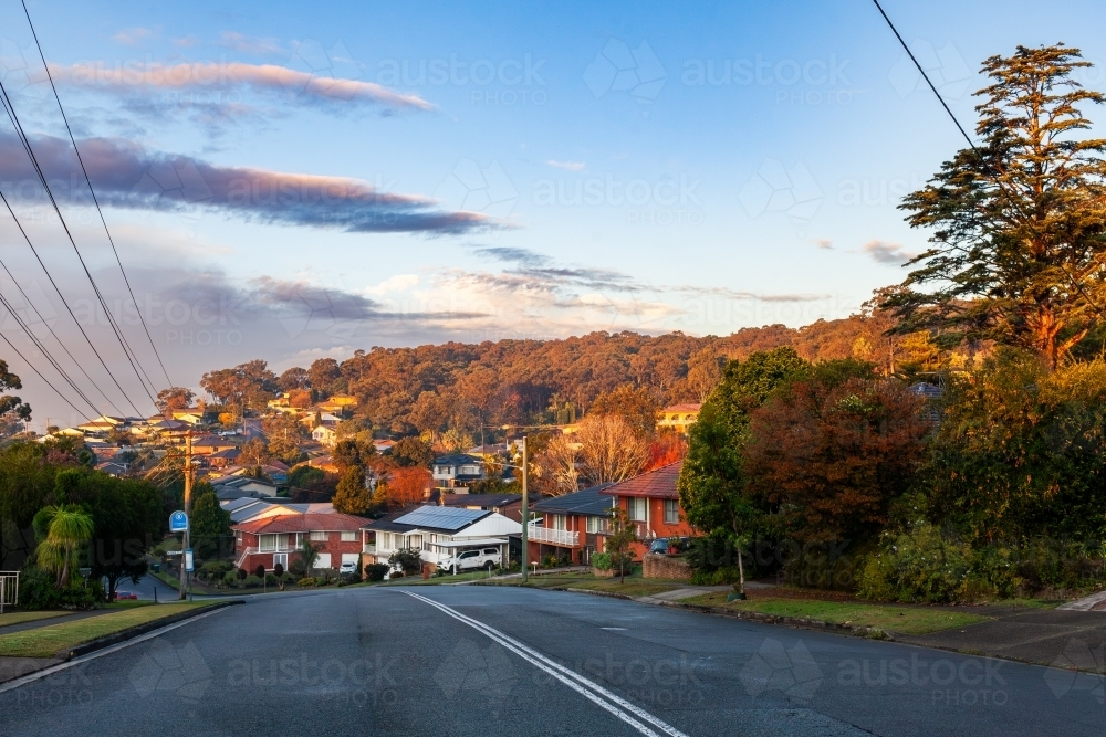 Road in shadow with sunset light on houses and hill in Wallsend - Australian Stock Image