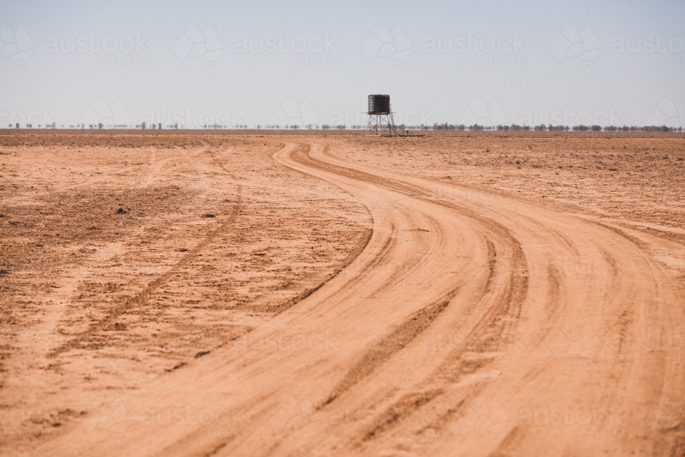 Road leading to a tank in a barren paddock - Australian Stock Image