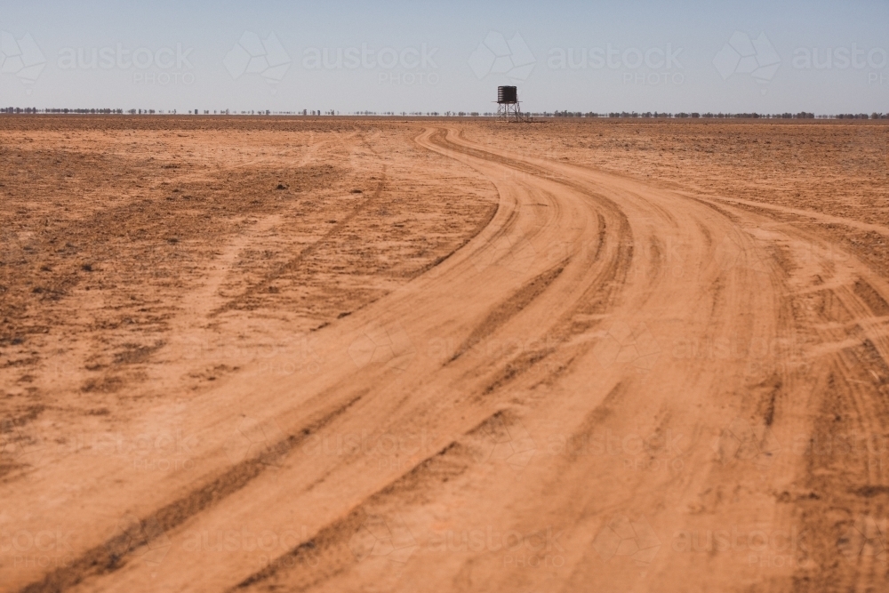 Road leading to a tank in a barren paddock - Australian Stock Image