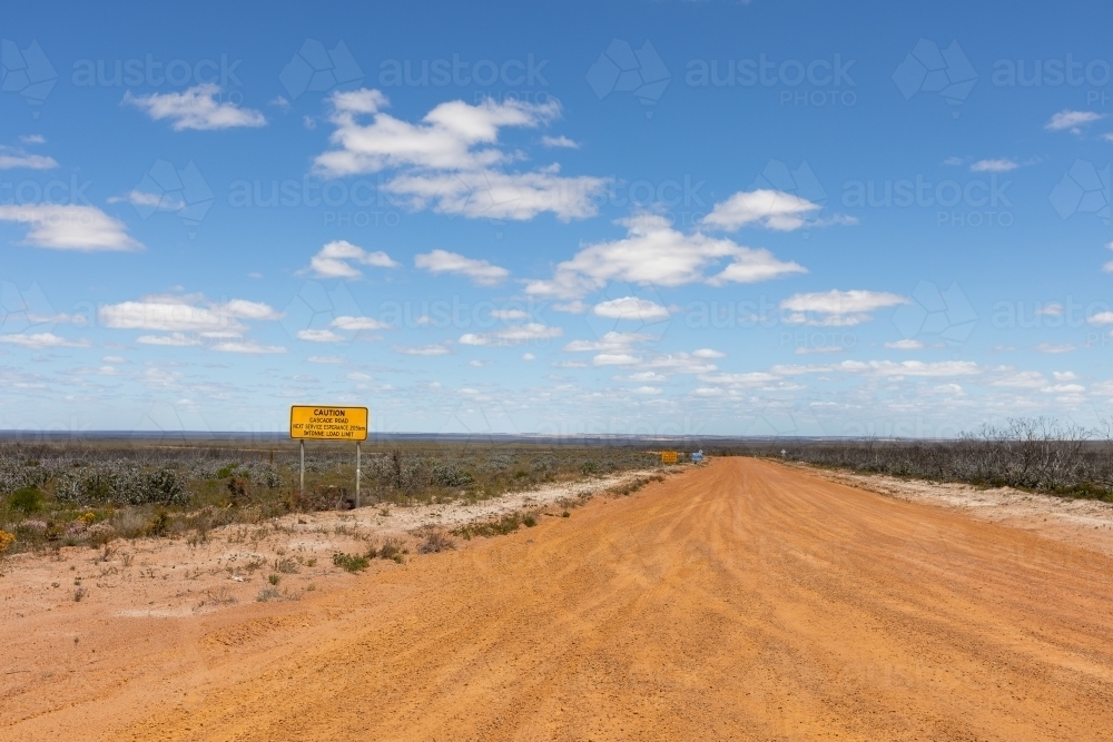 road sign beside gravel road in flat landscape - Australian Stock Image