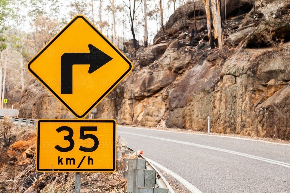Road sign showing sharp bend ahead in Putty Road after fire - Australian Stock Image