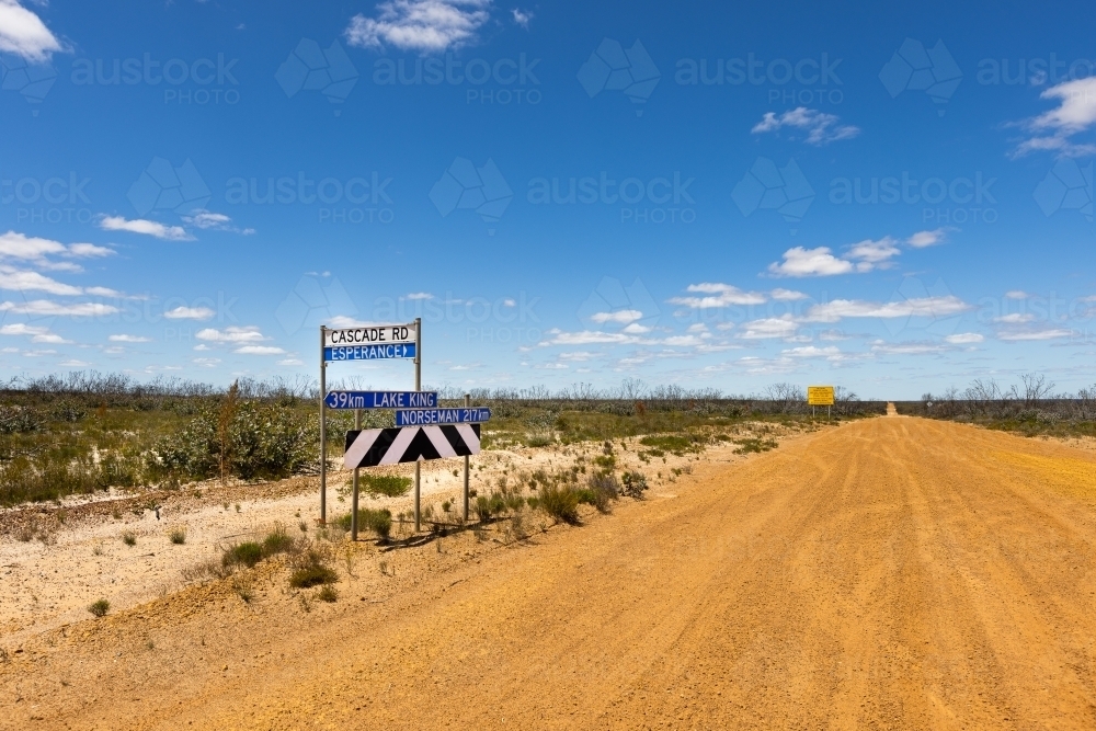 road signs on a gravel road with blue sky and flat horizon - Australian Stock Image