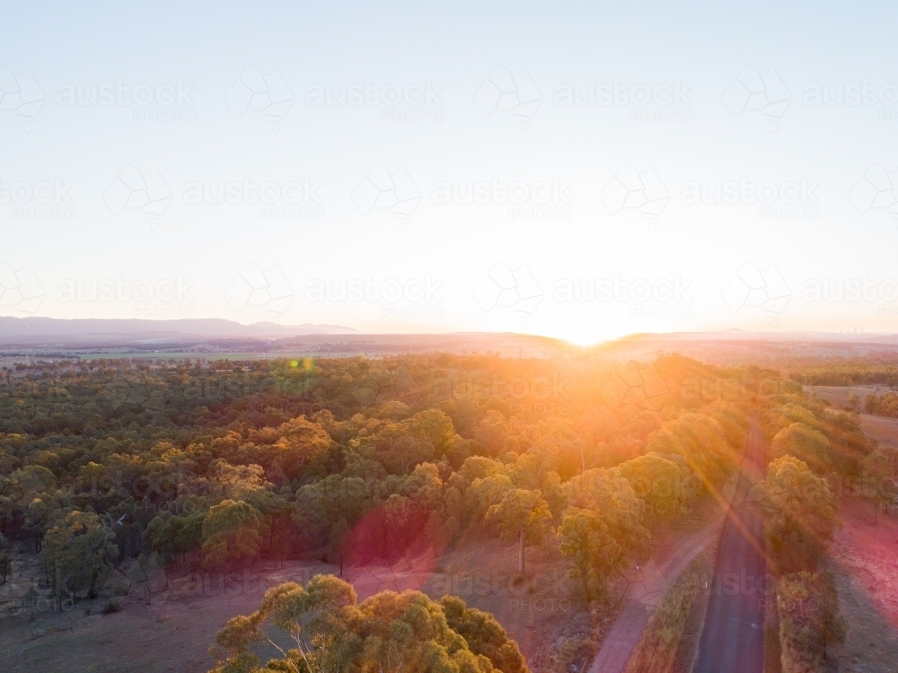 Road towards the sunset with trees beside - Australian Stock Image