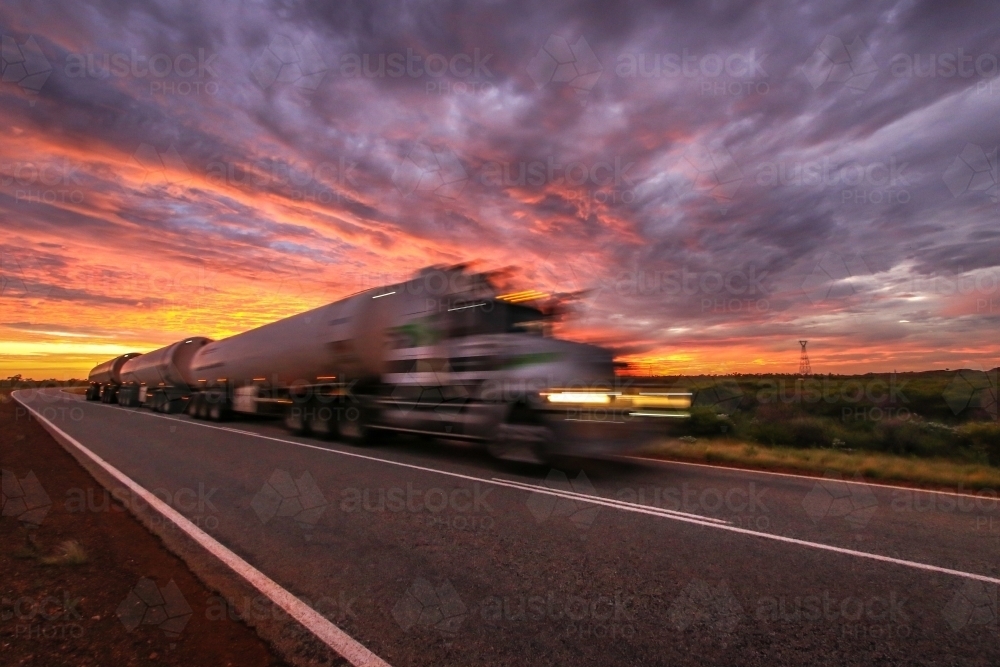 Road Train travelling along road at sunrise - Australian Stock Image