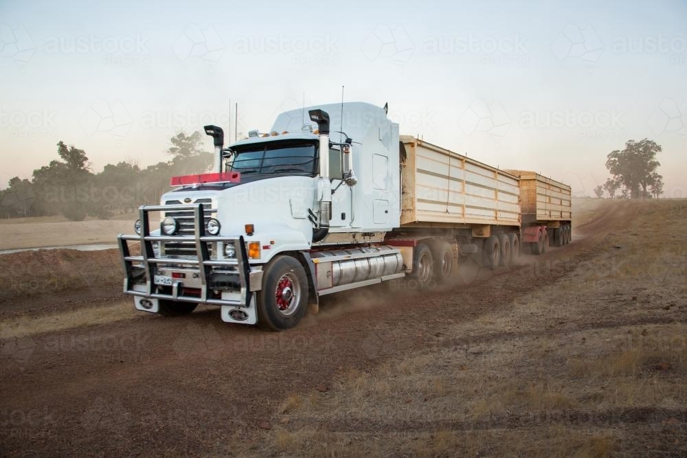 Road train truck transporting grain on an unsealed farm road - Australian Stock Image