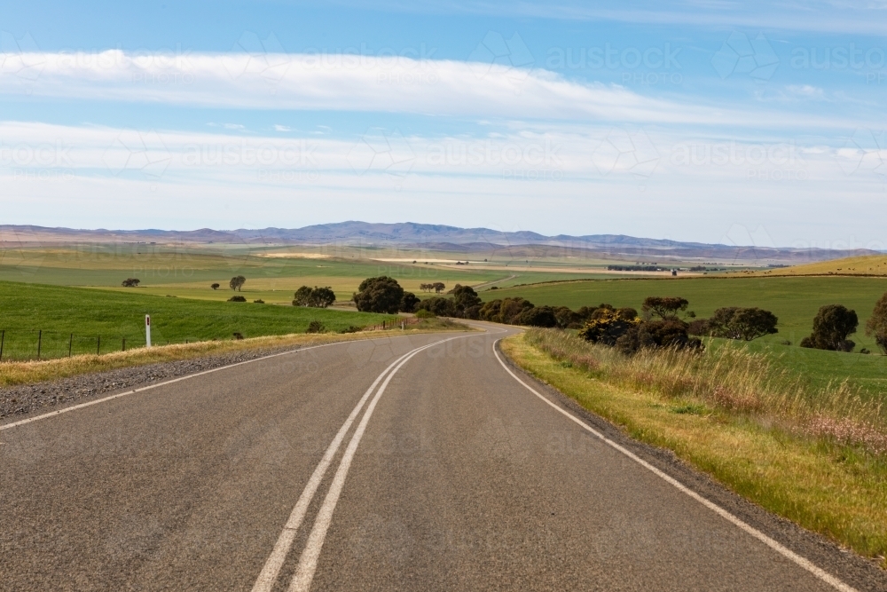road winding through green farm land - Australian Stock Image