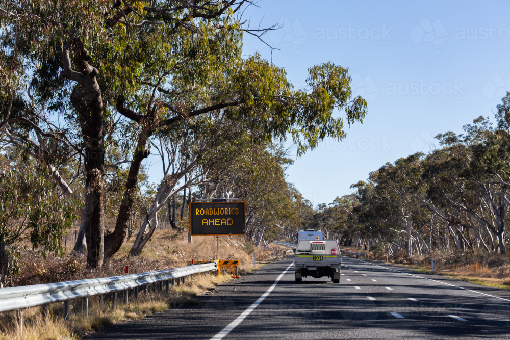 road work ahead sign and vehicle driving along rural highway in NSW Australia - Australian Stock Image