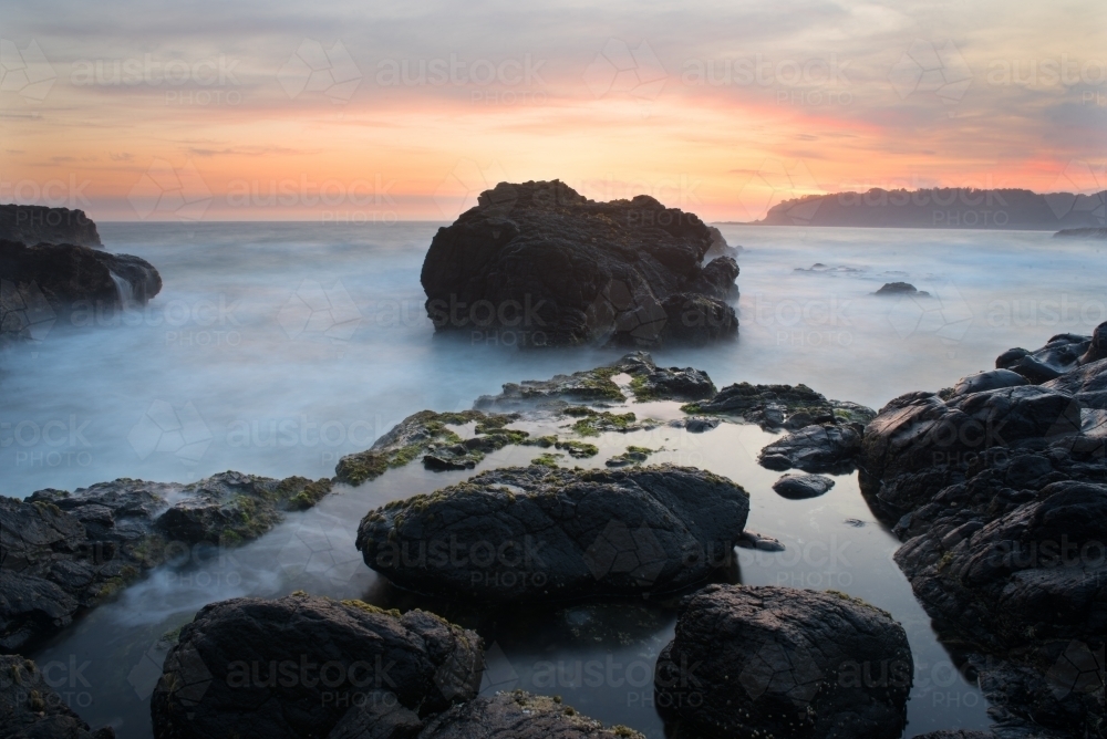 Rock in the ocean taken at dawn taken with long exposure - Australian Stock Image