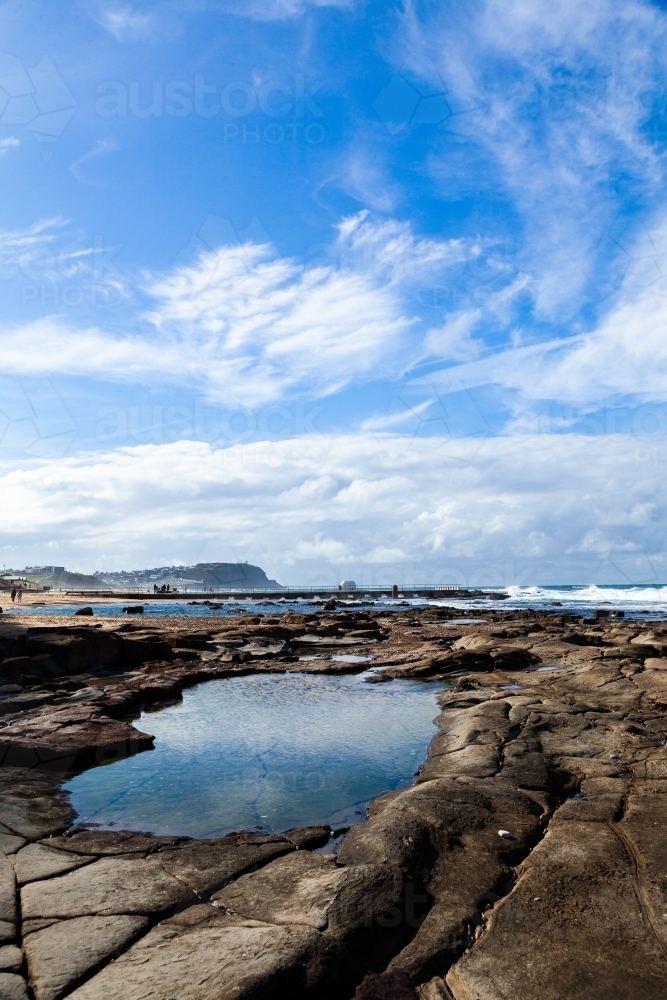 Rock pool reflecting the sky at beach - Australian Stock Image