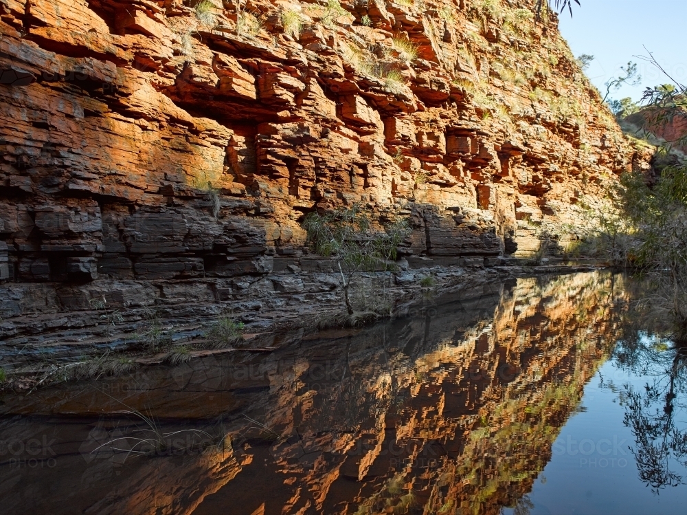Rock wall reflected in a pool at a remote gorge - Australian Stock Image