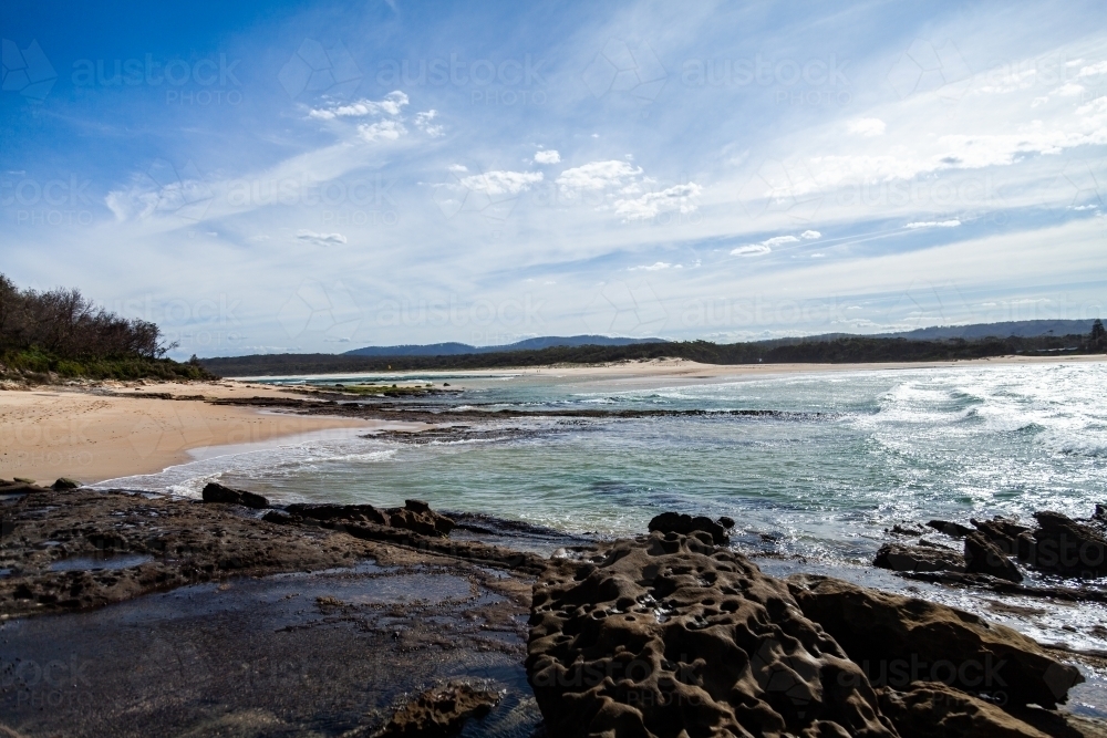 Rocks and ocean waves washing up on deserted beach of Crampton Island - Australian Stock Image