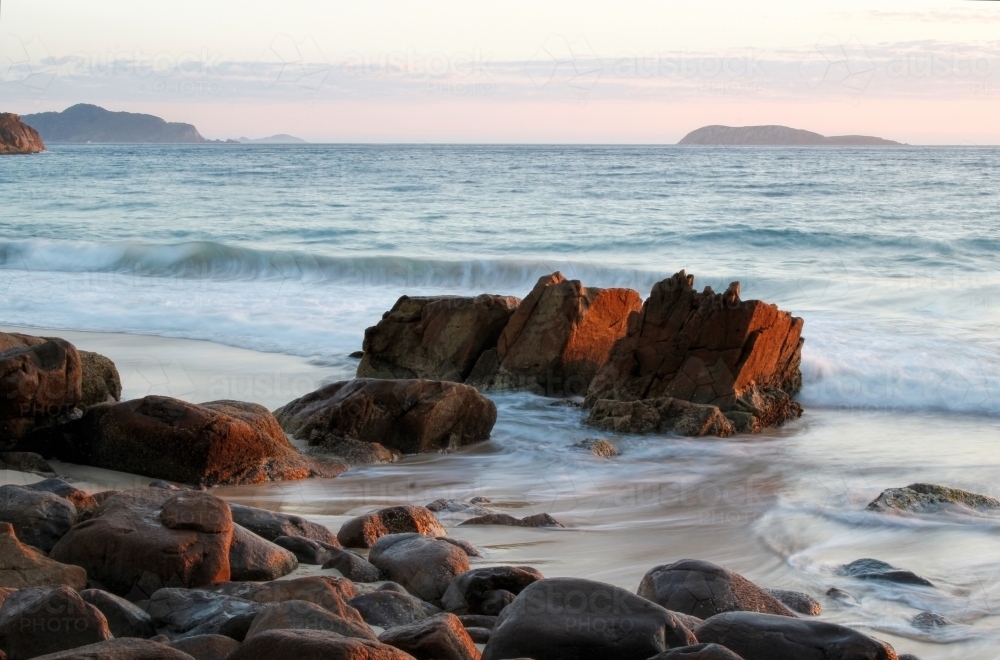 Rocks at the end of the ocean at sunrise - Australian Stock Image