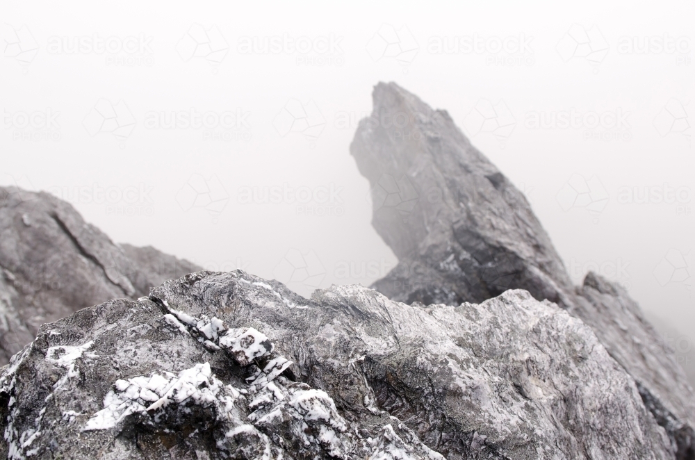 Rocks covered in patchy snow and mist - Australian Stock Image
