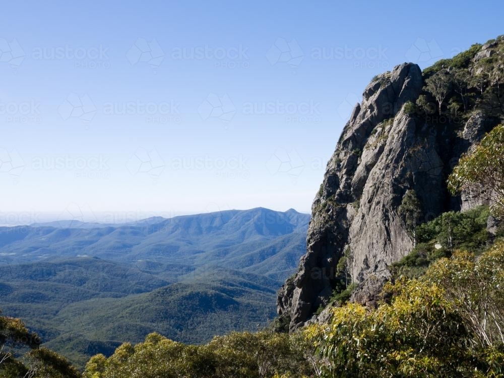 Rocky cliff face towering above mountain valleys - Australian Stock Image