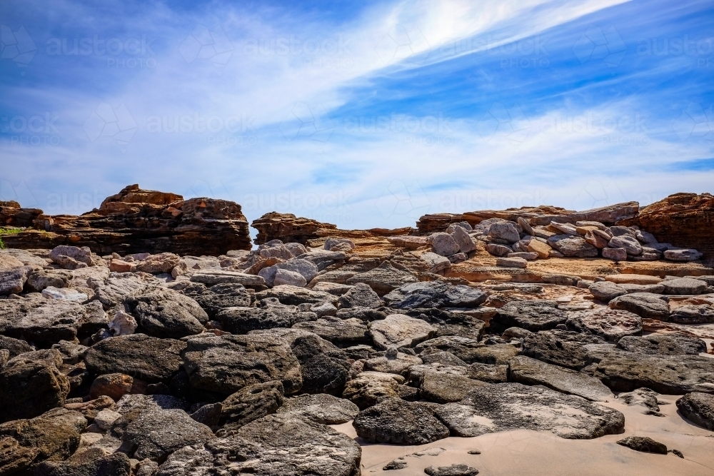 Rocky coastline against cloudy blue sky - Australian Stock Image