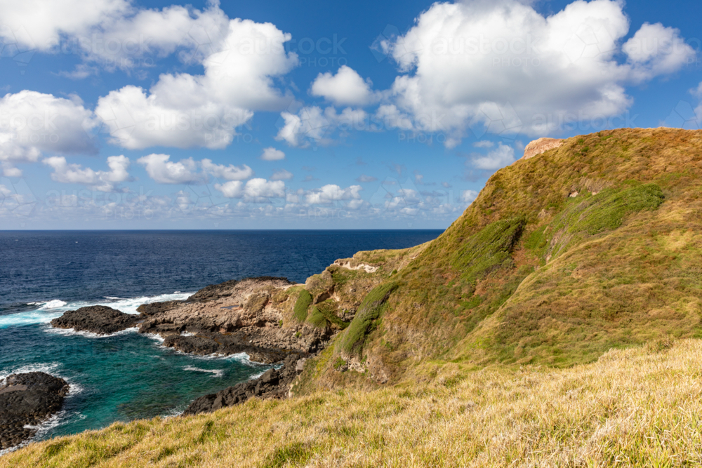 Rocky coastline with blue sky and white clouds - Australian Stock Image