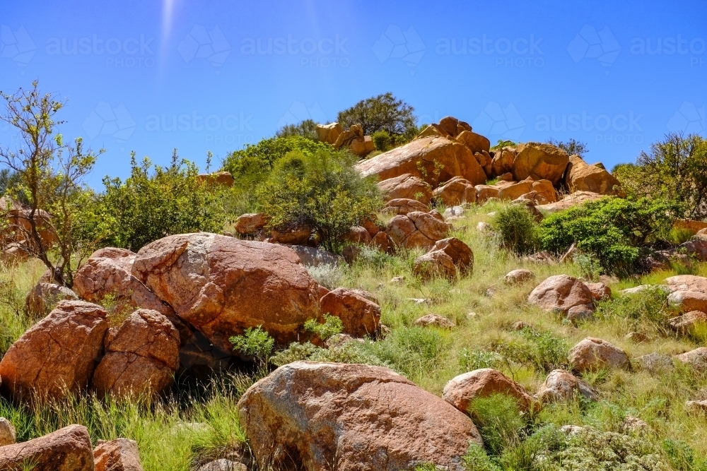 Rocky mountain on coastline beneath blue sky - Australian Stock Image