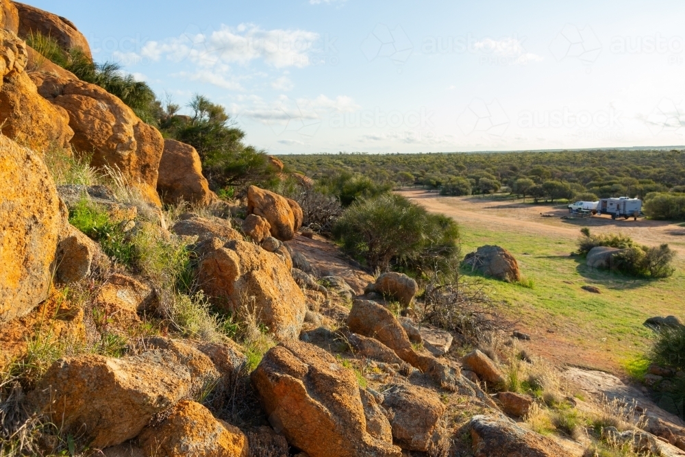 rocky outcrop and bush with caravan in distance - Australian Stock Image