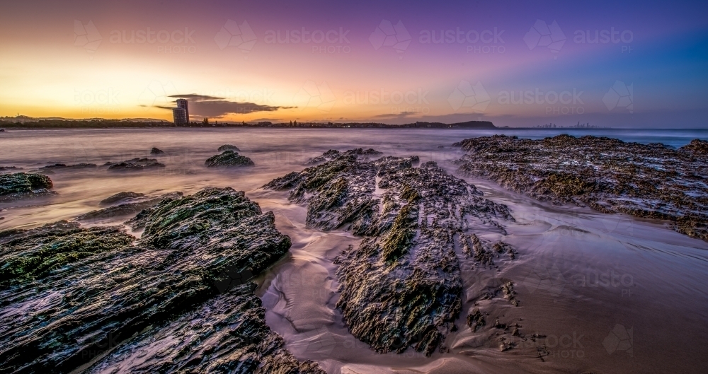 Rocky seascape sunset with the Gold Coast city backdrop - Australian Stock Image