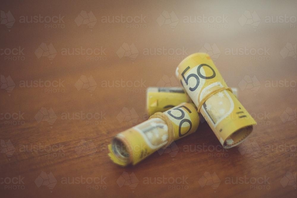 Rolled 50 dollar notes sitting on the table. - Australian Stock Image