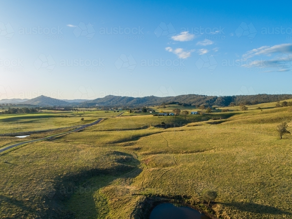 Rolling green hills and farm paddocks beside country road in Hunter Valley - Australian Stock Image