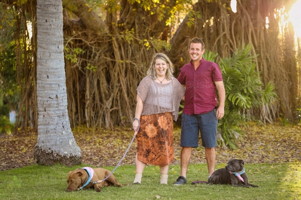 Image of Romantic couple standing together in park with two dogs on ...