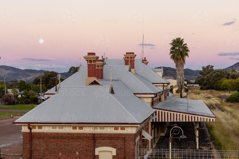 Rooftop of the historic Mudgee Railway Station with full moon in pink and purple twilight sky - Australian Stock Image