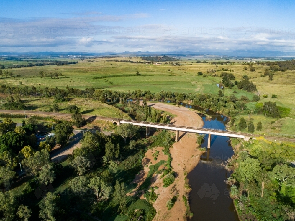 Rose Point and railway bridge over hunter river with farm paddock beyond in bright sunlight - Australian Stock Image