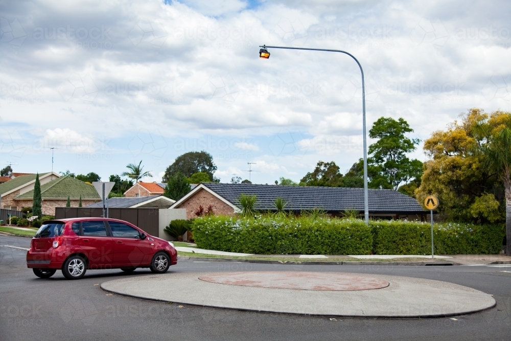 Roundabout in suburban Sydney with red car driving past - Australian Stock Image