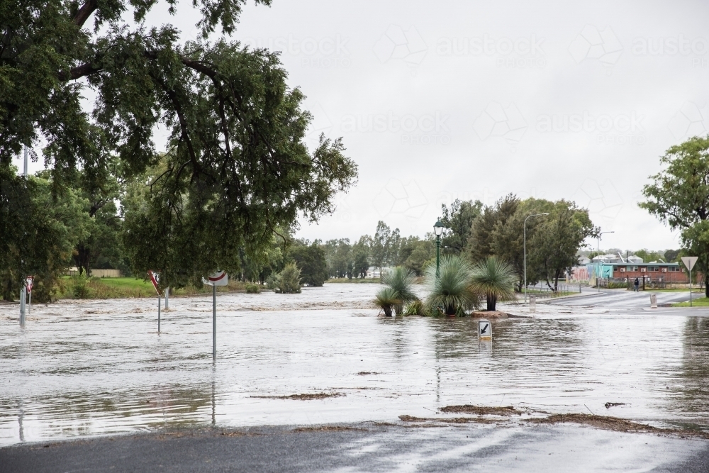Roundabout on main road in town closed with flooded river - Australian Stock Image